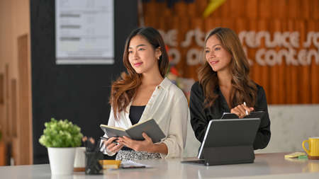 Motivated two businesswomen at work, smiling with passion, concept of successful businesswomen.の写真素材