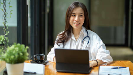 Happy young asian female physician using digital tablet computer in the office. medical people with technology concept.の写真素材