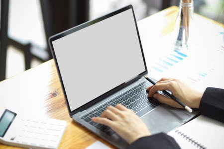 Female business financial worker working and managing financial data on laptop computer. notebook blank screen mockup.の写真素材