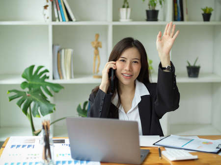 Successful businesswoman having a phone call with her business partner. female entrepreneur talking on the phone in office.の写真素材