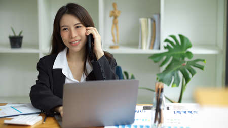 An asian young female worker talking on the phone, discuss works on telephone in the office.の写真素材