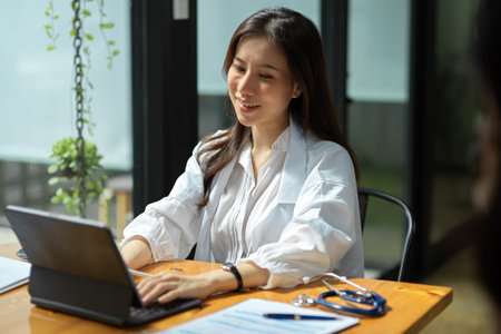 A beautiful female doctor, therapist, physician working on her modern digital portable tablet touchscreen computer in the office.の写真素材
