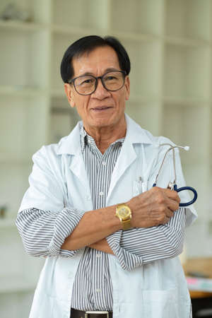 Portrait of Successful and confident middle-aged specialist male doctor crossed arms in white medical gown.の写真素材