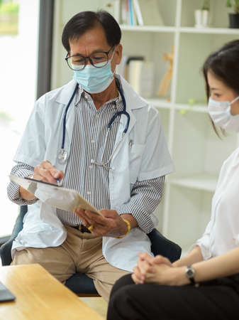A professionalÂ aged male psychologist examines his patient in a medical health centre. medical people concept.の写真素材