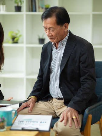 A middle-aged executive businessman in a formal suit sits in an office, talking with his marketing manager.の写真素材