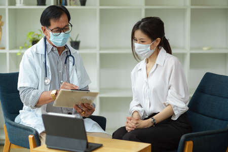 A professional-aged male physician inquires about a female patient's symptoms and takes on the medical notes.の写真素材