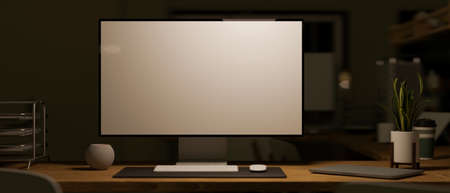 Modern pc computer white screen mockup on working desk in dark office room. 3d rendering, 3d illustrationの写真素材