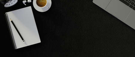 Copy space on black background with laptop computer, blank notebook, coffee cup. modern workspace...