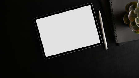 Top view of tablet with white screen display and open notebook on black background. top view, flat layの写真素材