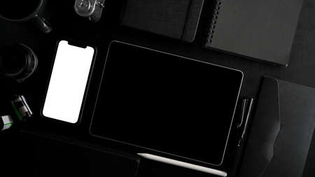 Top view, flat lay. close-up image of modern black workspace and electronic devices, tablet computer, smartphone, camera and books on black background.の写真素材