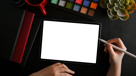 Close-up female using tablet blank screen mockup on black background. photographer, editor workspace concept. top viewの写真素材