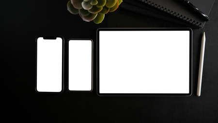 Digital tablet computer and two smartphone blank screen mockup on black background. top view, flat layの写真素材