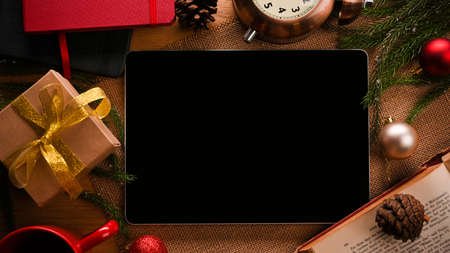 Tablet computer blank screen mockup on table surrounded by Christmas decorations. Christmas festive holiday with technology concept.の写真素材