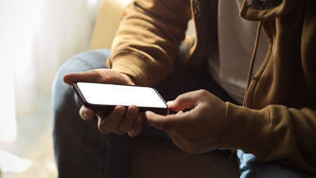 A man texting message on smartphone, using smartphone, holding mobile phone white screen mockup. cropped imageの写真素材