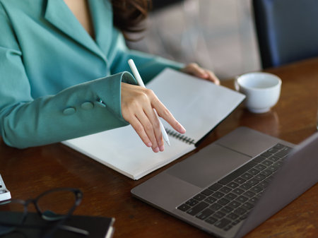 A successful businesswoman works on a marketing project on her laptop computer at her office desk.の写真素材
