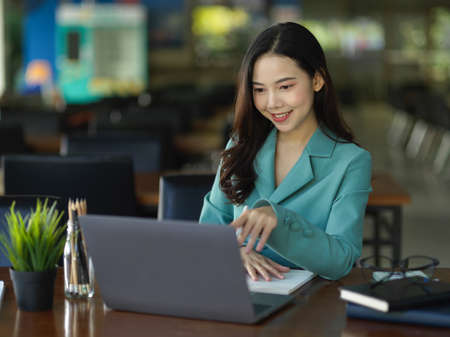 Professional and elegant businesswoman works on laptop computer in modern office working area.の写真素材