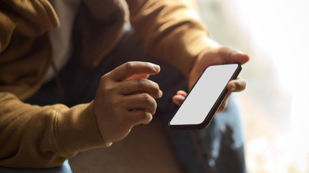 Businessman, male freelancer using a smartphone while sitting on sofa at his home. mobile phone blank screen mockup. close-up.の写真素材