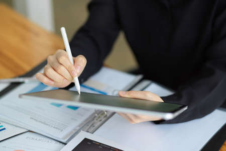 Cropped image of Businesswoman using stylus pen and wireless tablet computer at her workplace in office.の写真素材