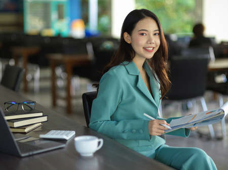 Positive businesswoman holding a clipboard with business financial data report at office working...
