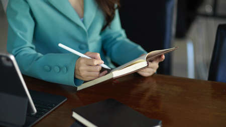 Cropped image of a beautiful woman reading and taking some notes on a book. study, knowledge,...