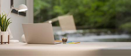 Modern luxury workstation with laptop computer and copy space for montage on tabletop over green forrest in the background. 3d rendering, 3d illustrationの写真素材