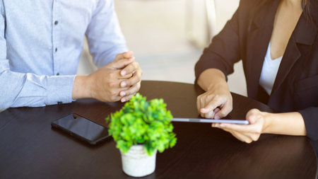 Cropped image of a businesswoman and businessman talking and discussing theirs work on tablet computer.の写真素材