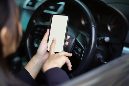 Close-up of a woman or businesswoman using modern smartphone in her car. mobile phone blank screen...