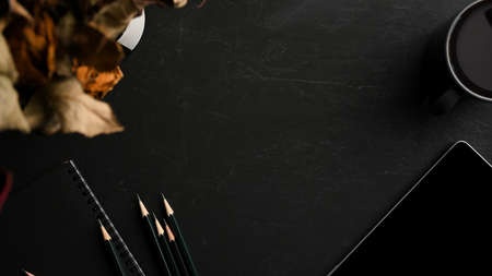 Copy space on black background with stationery, digital tablet computer, coffee cup and dry flowers in the border. top viewの写真素材