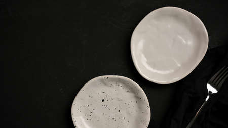 Copy space on black background with minimal empty ceramic plates and fork. top view, flat layの写真素材