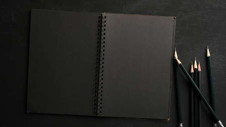 Empty modern black notebook with black papers and pencils on modern dark study table. top viewの写真素材