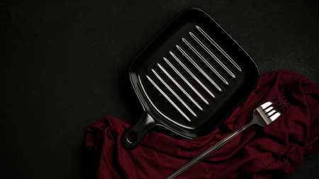 Modern black plate and fork with red napkin on black dining table. small pan plate. top view, flat layの写真素材