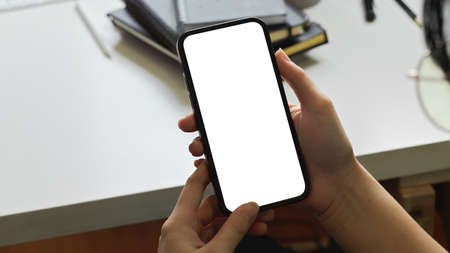 Cropped shot of a woman hands using smartphone mockup at the white office desk. Blank screen mobile phone for graphic display montageの写真素材