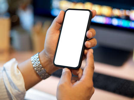 Close-up, Male hands holding modern smartphone blank screen mockup over his working desk.の写真素材