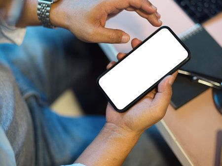 Close-up, top view image of a man using smartphone. texting, message, scrolling on phone. blank screen mockup.の写真素材