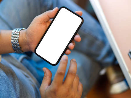 Close-up, a man using his smart mobile phone, sitting at his desk. phone blank screen for your banner mockup.の写真素材