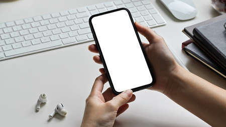 Close-up hands using smartphone on the table at the office. mobile phone blank screen mockup. device technology concept.の写真素材