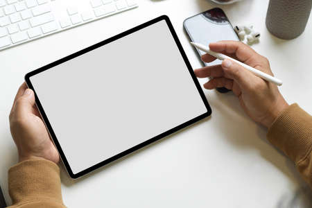 Close-up, a male freelancer working on his modern digital tablet computer at his workspace. tablet blank screen mockup.の写真素材