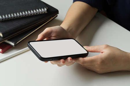Close-up view of businesswoman searching an informations on smartphone for her current project.の写真素材
