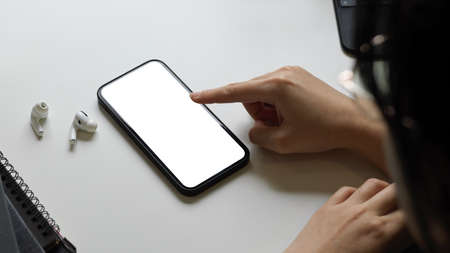 Close-up, a female pointing her finger on smartphone screen, touching screen, tapping on screen. smartphone blank display.の写真素材