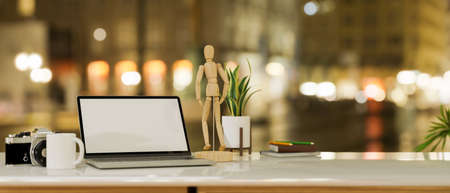 Close-up laptop computer blank screen mockup with accessories and copy space on table over blurred city night light in the background. 3d rendering, 3d illustrationの写真素材