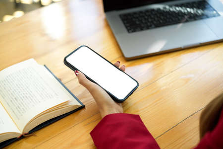 Close-up image of female holding smartphone on her working desk. businesswoman using mobile phone.の写真素材