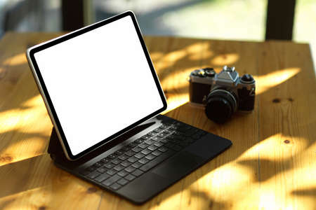 Close-up, Digital tablet computer in white screen mockup and camera on wooden table in modern officeの写真素材