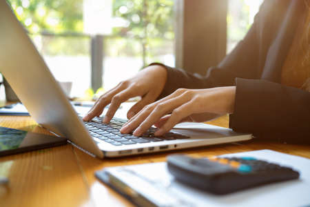 Cropped image of business woman working on laptop computer. Female assistant typing on laptop keyboard. Woman browsing internet via notebook computer.の写真素材