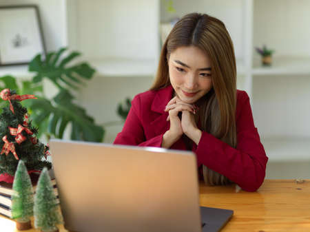 Beautiful asian young businesswoman concentrated with her work, waiting to receive the great news on email via laptop computer.の写真素材