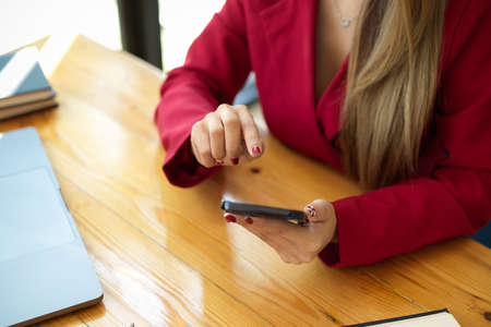 Close-up image of elegant businesswoman using smartphone to communicate with partners at the desk.の写真素材