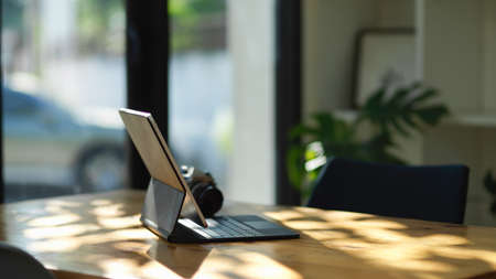 Side view image of a working desk with portable tablet computer and camera on wooden table. photographer desk.の写真素材