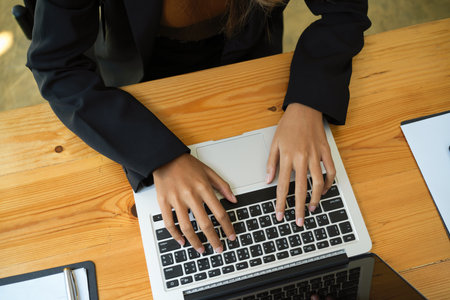 Close-up top view image of business woman or female worker typing on laptop computer's keyboard at...