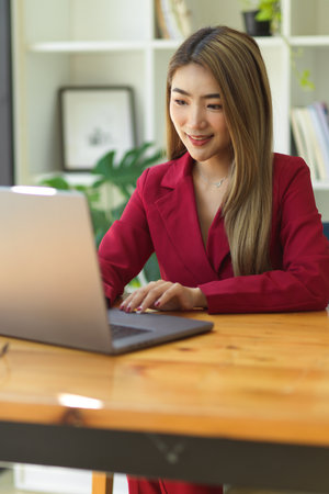 Portrait of gorgeous asian business woman working at her office workplace, using laptop computer.の写真素材