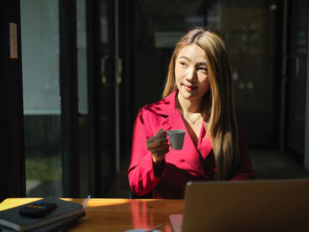 A female freelancer or business woman in a coffee shop, sips a shot of espresso to refresh her day.の写真素材