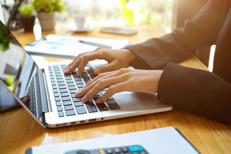 Cropped shot of female or business woman working on digital laptop computer at her desk. searching on the internet, typing on keyboard, email to business partners.の写真素材
